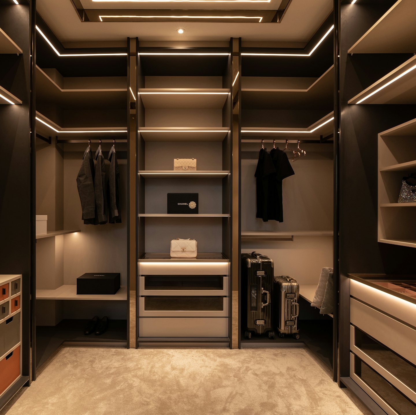 Modern walk-in closet with organized clothing and luxury luggage.