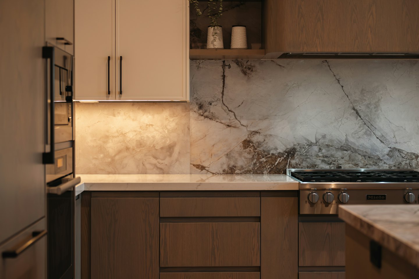 Modern kitchen with wood cabinets and marble countertops.